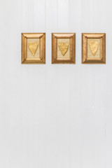 Gold hearts hanging on white wooden background. Copy space.