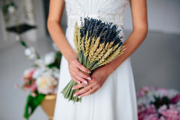 The bride holds a bouquet of lavender
