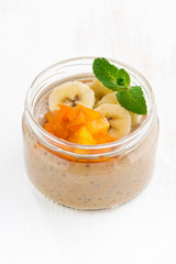 Banana dessert with persimmons in a glass jar, vertical