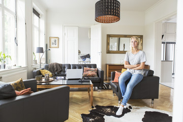 Full length of teenage girl sitting on sofa in living room at home