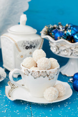 White chocolate and coconut candy in cup on wooden blue table with Christmas and New Year decor