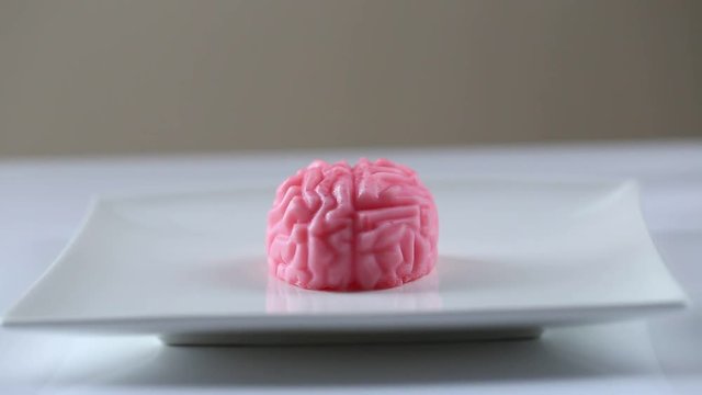 berry pink jelly in the form of a brain on a white square plate
