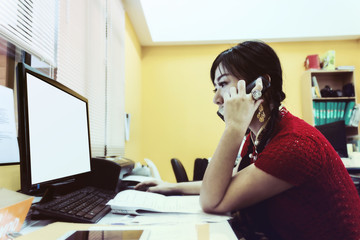 Obraz na płótnie Canvas Asian women looking computer screen talk on telephone in office