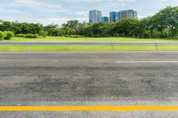 Plakat Side view of asphalt road with park in city.