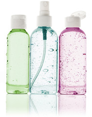 three toiletry bottles with water droplets on white background
