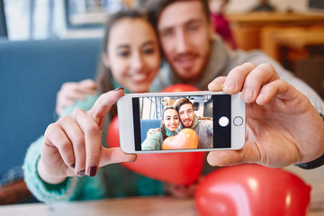 man and woman doing selfie with balloon in the form of heart in a cafe. Two people communicate, laughing and enjoying the time spending with each other. Couple in love on a date. Love story and