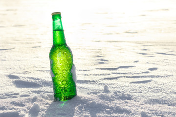 Bottle of cold beer on the snow. Close up view.
