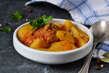 Homemade stew with meat and vegetables on a black background