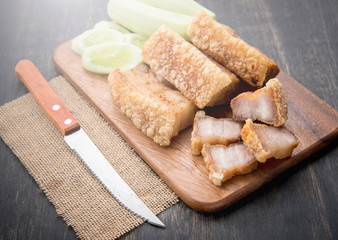 Fried pork belly with knife on wooden chopping board
