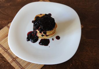 Homemade sweet pancakes with fruit jam on a white plate, top view with copy space