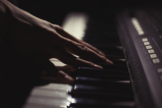 Playing on synthesizer keyboard on black background