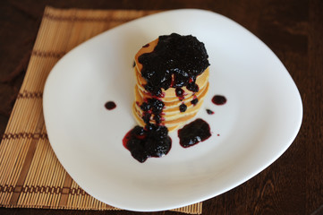 Homemade sweet pancakes with fruit jam on a white plate, top view with copy space