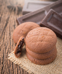 Chocolate cookies with chocolate bar on wood background