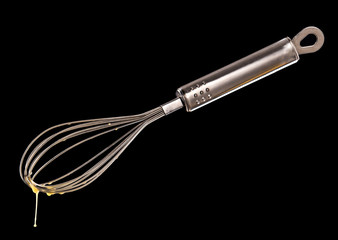 Wire whisk with dripping Egg isolated on black background