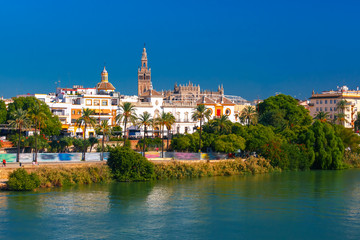 Fototapeta na wymiar Quay of the river Guadalquivir, Plaza de toros de la Real Maestranza de Caballeria and Giralda in the sunny day, Seville, Andalusia, Spain