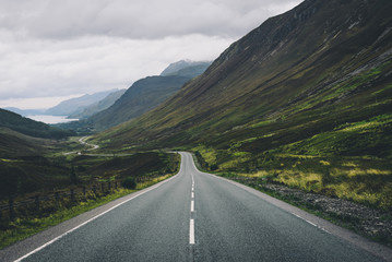 Empty road passing through grassy landscape
