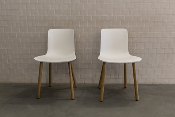 Two white chairs by wall