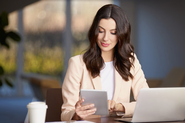 Exploring modern technology. Shot of a confident professional female using digital tablet while sitting at office in front of computer.