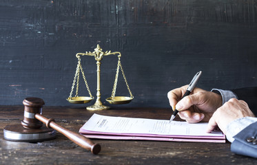 Man signing document with gavel and justice scale