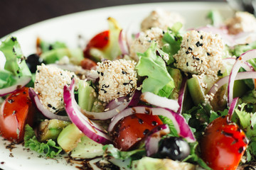 Salad with greens,cheese and onions on a white dish