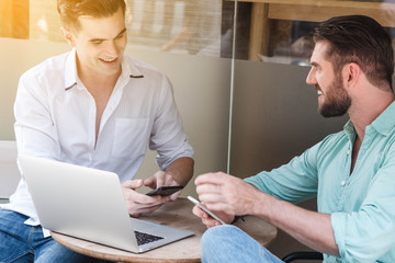 Obraz premium Two Westerner Business men working with laptop and smartphone to