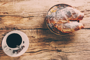 Coffee and croissant on wooden background