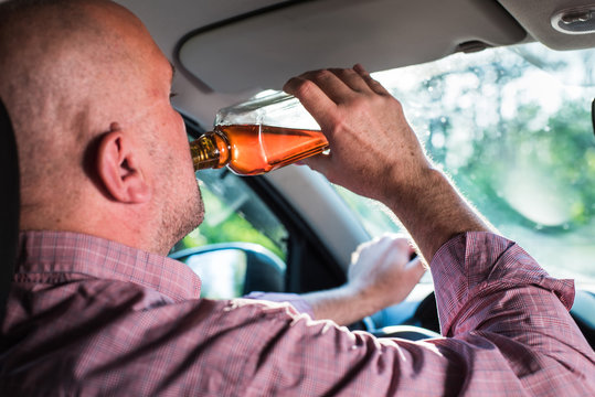 Man drinking alcohol in the car. 