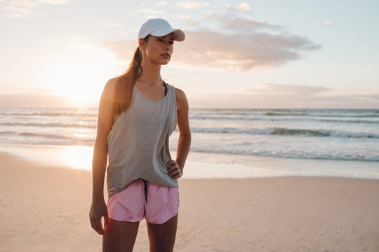 Fitness model in sportswear standing on the beach