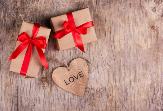 Two small boxes with a red bow and Valentine on the old wooden background. Copy space. Valentine's Day.