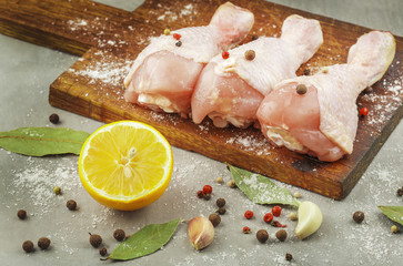 raw chicken legs with lemon on a wooden board