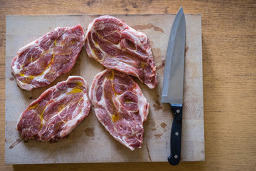 Top view of raw pork chop steaks ready for a grill. Preparing a raw meat by chef knife. Pork chops on a wooden cutting board ready for cooking.