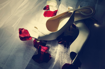 Wedding white sandals and rose-petals on a white veil
