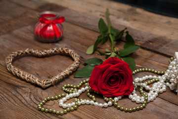 Dating in vintage style, red rose on wooden background with heart shaped, candle and bead. Present on Valentine's day, original congratulation.