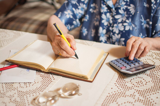 Unrecognizable senior woman calculating financial  bills at home.