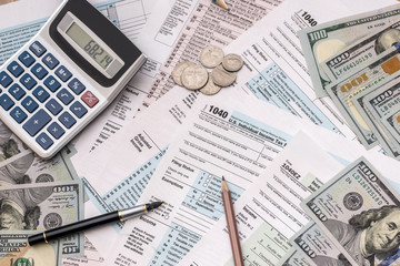 money, tax form, calculator and pen on desk.