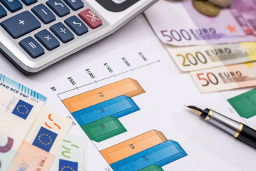 Euro notes above business graph, pen and calculator.