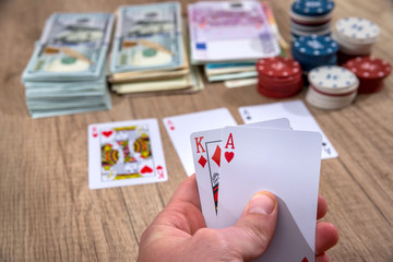 man holding play card. poker chips, us dollar.