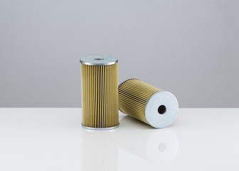 two automotive filter cylindrical shape  on a white background with reflection