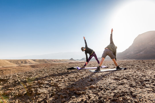 Young couple training yoga exercise asana desert morning sunrise