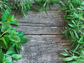 Obraz premium Frame of fresh herbs - rosemary, savory, mint on an old wooden background 