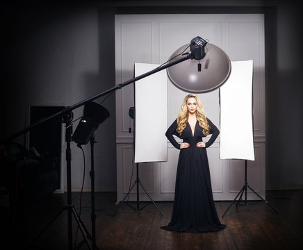 Beautiful model posing in black dress in photo studio. Fashion, vogue, glamour concept.