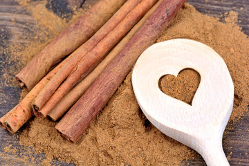 Wooden spoon with cinnamon sticks and powder