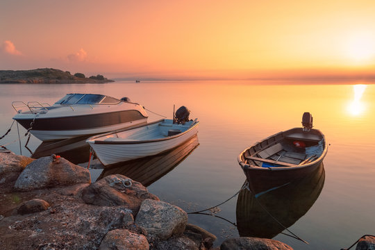 Three Motor Fishing Boats At The Pier On North Sea, Sweden Coast Line. Sunrise Scenery, Dramatic Sky In Red Shades, Beautiful Sea Landscape.