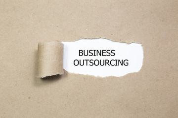 business outsourcing word written under torn paper.