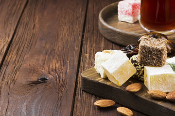 Fototapeta na wymiar Black tea, oriental sweets, dates and nuts on a dark wooden back