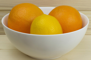 fresh juicy natural apples and oranges in a shiny white plate on wooden background