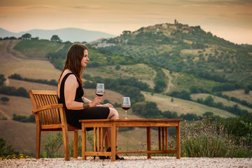 Girl with a glas of wine at sunset in Tuscany, Italy