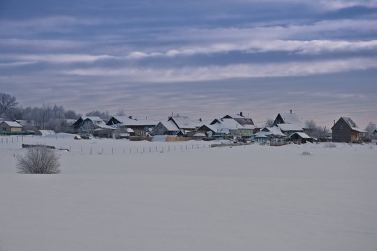 Winter photo of the village on the background of snowy fields an