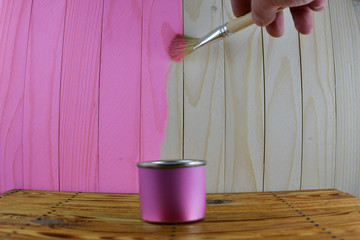 Jar with pink paint and brush in hand paint wooden background
