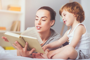 Delighted mother reading a fairytale to her son.